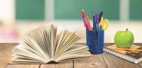 Book, pencils and an apple on a table