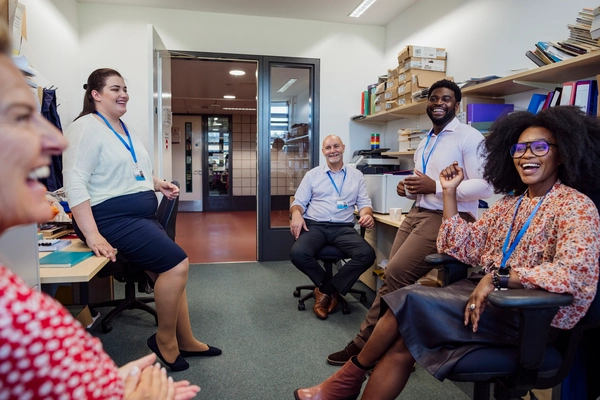 Teachers in an office together in the school that they work at in Gateshead, North East England. They are taking a break from teaching and laughing with each other.