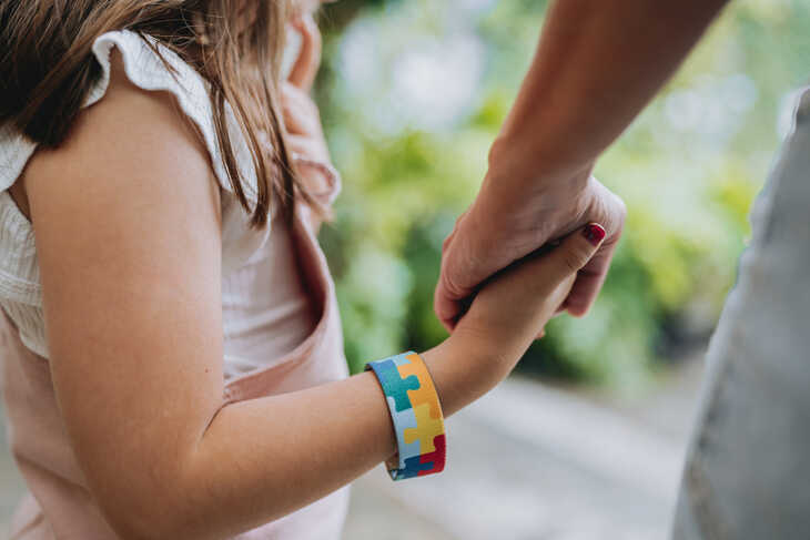 Autistic child holding hands with her mother