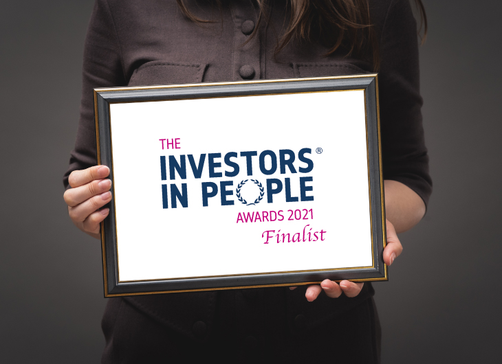 A person is holding a frame with an image that says: "THE INVESTORS IN PEOPLE AWARDS 2021 Finalist"