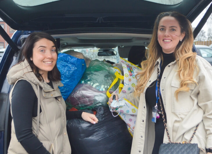 Two New Directions employees stand next to a car full of Ukraine aid.